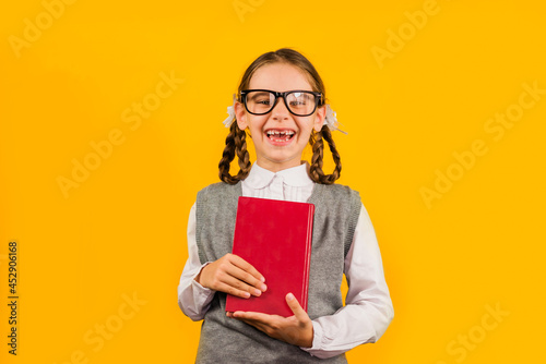 Back to school. Happy child holds a book in her hand on a yellow background. Education and intellectual development of children. World book day.
