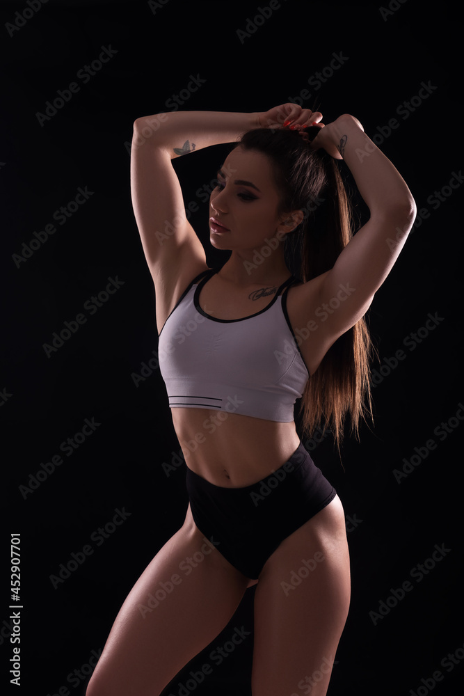 Fit brunette woman doing exercises in studio on neutral background. Flawless sporty body in sportswear outfit. Space for text Fit brunette woman doing exercises in studio on neutral background. Flawless sporty body in sportswear outfit. Space for text