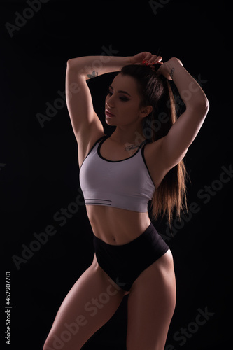 Fit brunette woman doing exercises in studio on neutral background. Flawless sporty body in sportswear outfit. Space for text