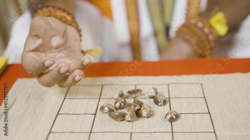 Close up shot of astrologer hands placing cowrie shells on chart and counting to predict future - Concept of Indian horoscope or fortune telling