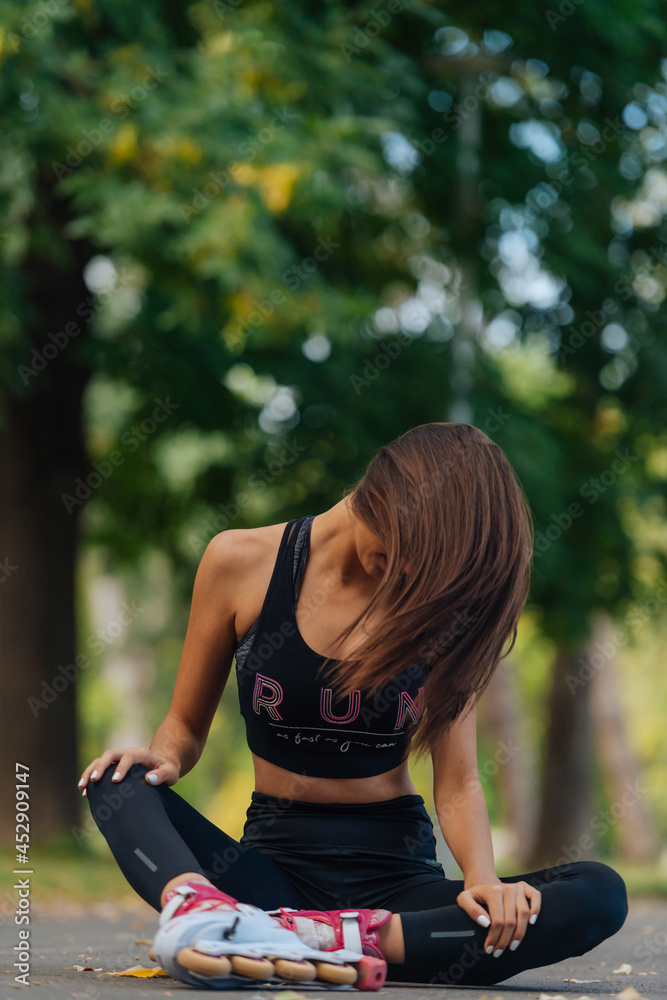 Closeup portrait of a beautiful sportive young brunette with rollerskates sitting on the road and playing with her long beautiful hair Closeup portrait of a beautiful sportive young brunette with rollerskates sitting on the road and playing with her long beautiful hair