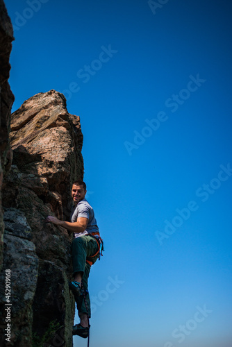 Young handsome sportsman getting ready to climb a rock cliff