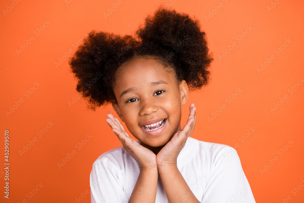 Photo of small cute girl hands face wear white t-shirt isolated on orange color background Photo of small cute girl hands face wear white t-shirt isolated on orange color background