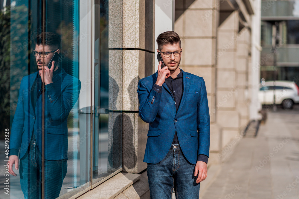 Portrait of attractive businessman standing outside and having mobile phone conversation Portrait of attractive businessman standing outside and having mobile phone conversation