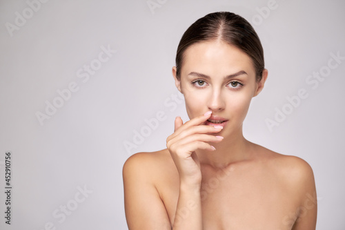 Beautiful Young Woman with Clean Fresh Skin standing over light grey background