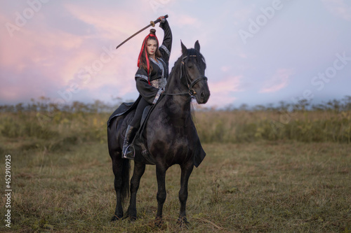 A warrior girl in a black kimono on a black horse with a katana in her hands photo