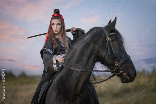 Warrior girl in black kimono on a raven horse with a sword on her shoulder