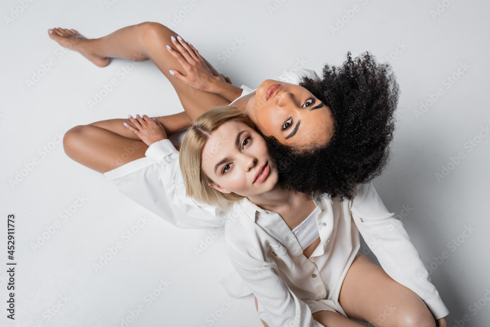 Naklejka premium top view of african american and blonde models looking at camera on white