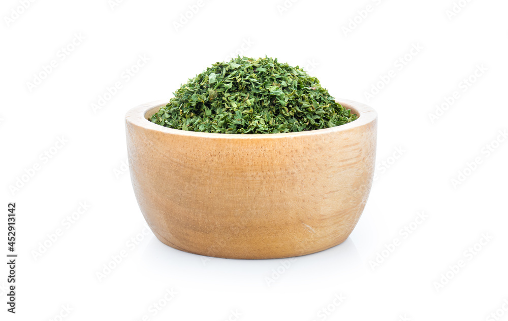 dried parsley in wooden bowl isolated on white background. dried parsley in wooden bowl isolated on white background.
