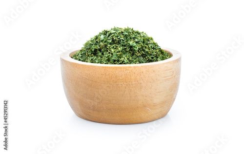 dried parsley in wooden bowl isolated on white background.