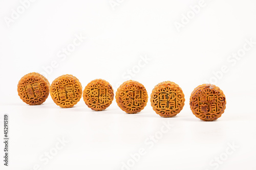 Golden moon cakes on a white background.The moon cakes are engraved with "red bean sand , marinated meat , egg yolk and strawberry moon cakes"