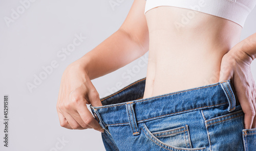 Close up slim woman measuring her thin waist. Healthcare and woman diet lifestyle concept to reduce belly and shape up healthy stomach muscle.