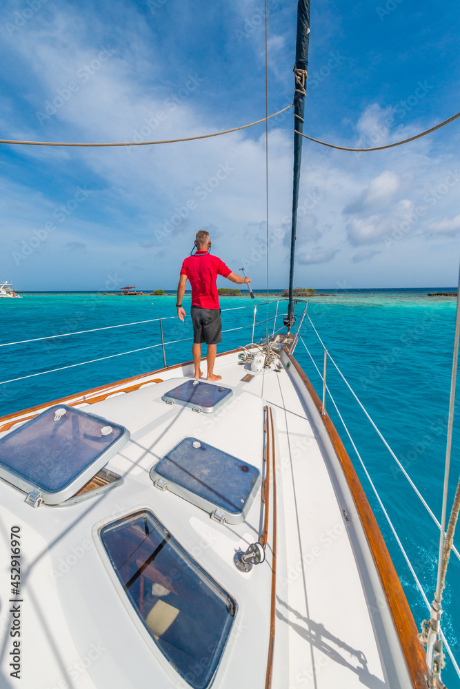 Man enjoying sailing trip on a luxury summer holiday vacation, sunny weather and ocean in background on a beautiful yacht Man enjoying sailing trip on a luxury summer holiday vacation, sunny weather and ocean in background on a beautiful yacht