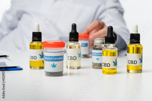 cropped view of blurred physician near containers and vials with medical cannabis medication isolated on white