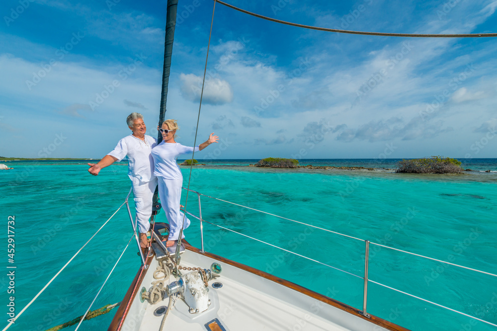 Senior couple enjoying sailing trip on a luxury summer holiday vacation, sunny weather and ocean in background, love and romance on a beautiful yacht