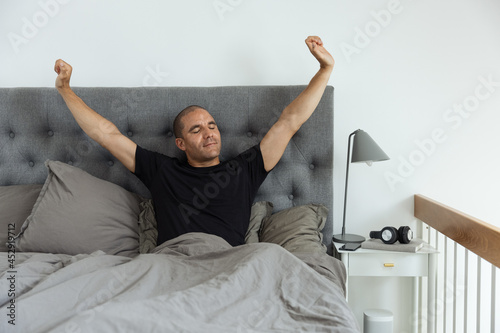 Content man stretching on bed after awakening