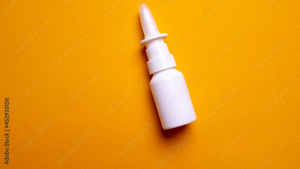 Bottle of nose drops on a yellow background close-up. Spray for the nose. View from above Bottle of nose drops on a yellow background close-up. Spray for the nose. View from above