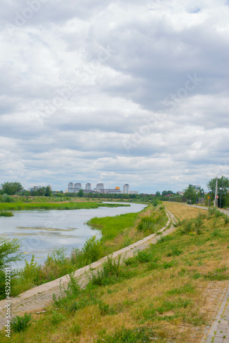 river and blue sky with clouds and green field