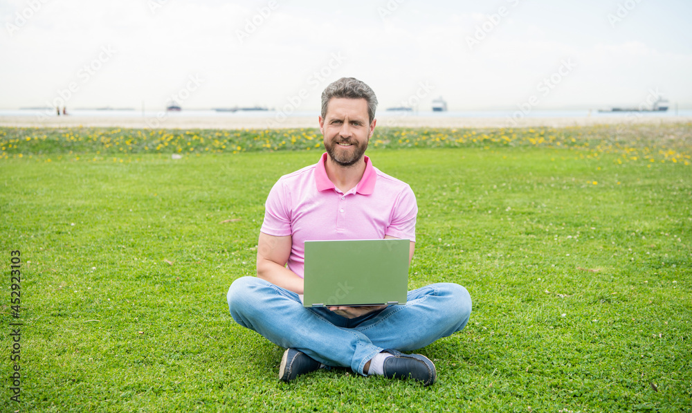 happy businessman using laptop for blogging on green grass, freelancer happy businessman using laptop for blogging on green grass, freelancer