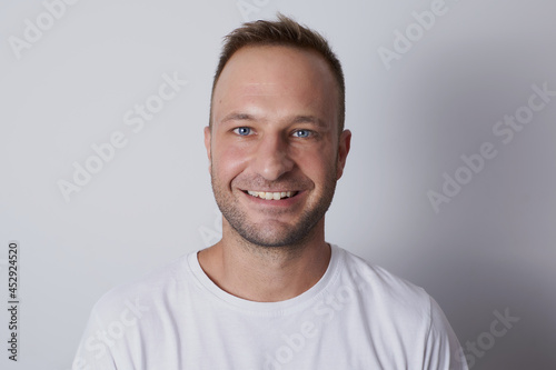 Man smiling in a white background with white t-shirt