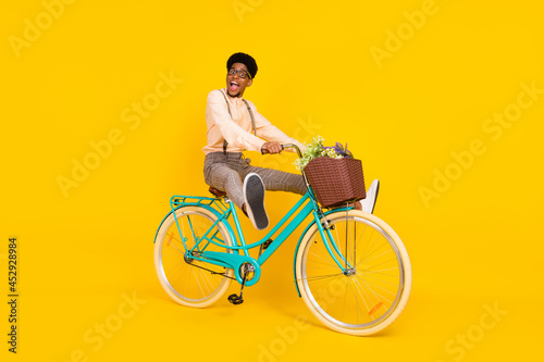 Photo of funky careless crazy nerd guy ride bicycle raise legs wear suspenders shirt isolated yellow color background