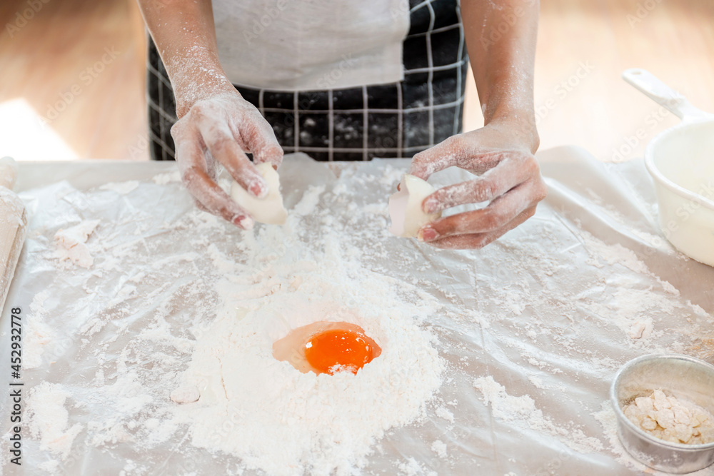 A woman is mixing flour and eggs with her hands before kneading the dough to make bread.