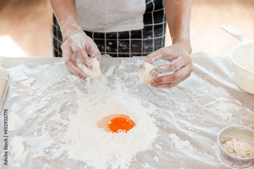 A woman is mixing flour and eggs with her hands before kneading the dough to make bread. A woman is mixing flour and eggs with her hands before kneading the dough to make bread.