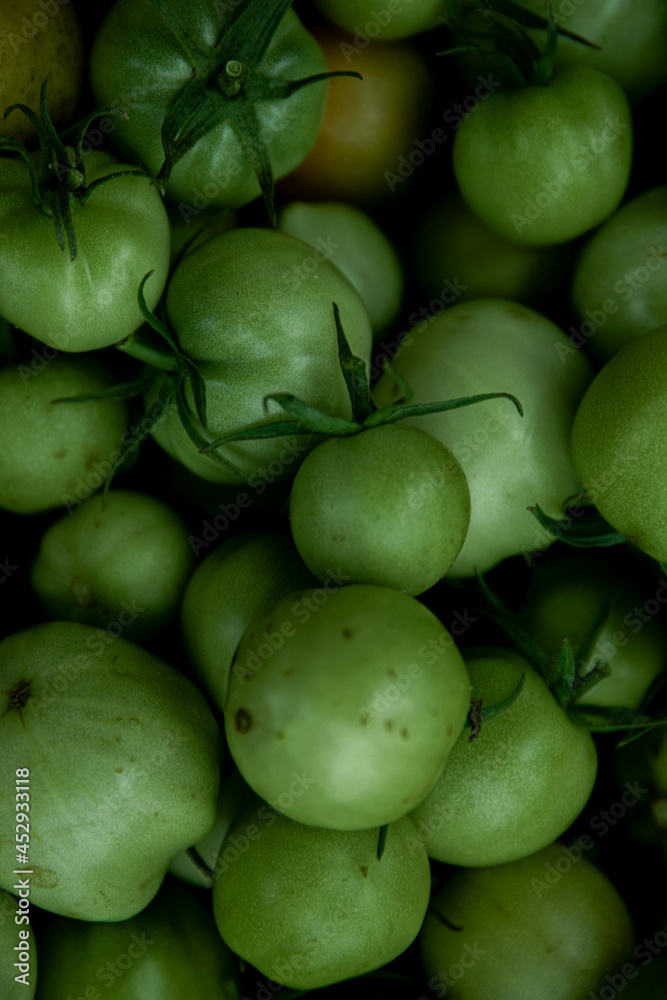 reen tomato (unripe) in wicker basket on wooden background. Unripe green tomato in bowl for fried dish or salted pickled vegetables. Raw green tomato on table for dinner