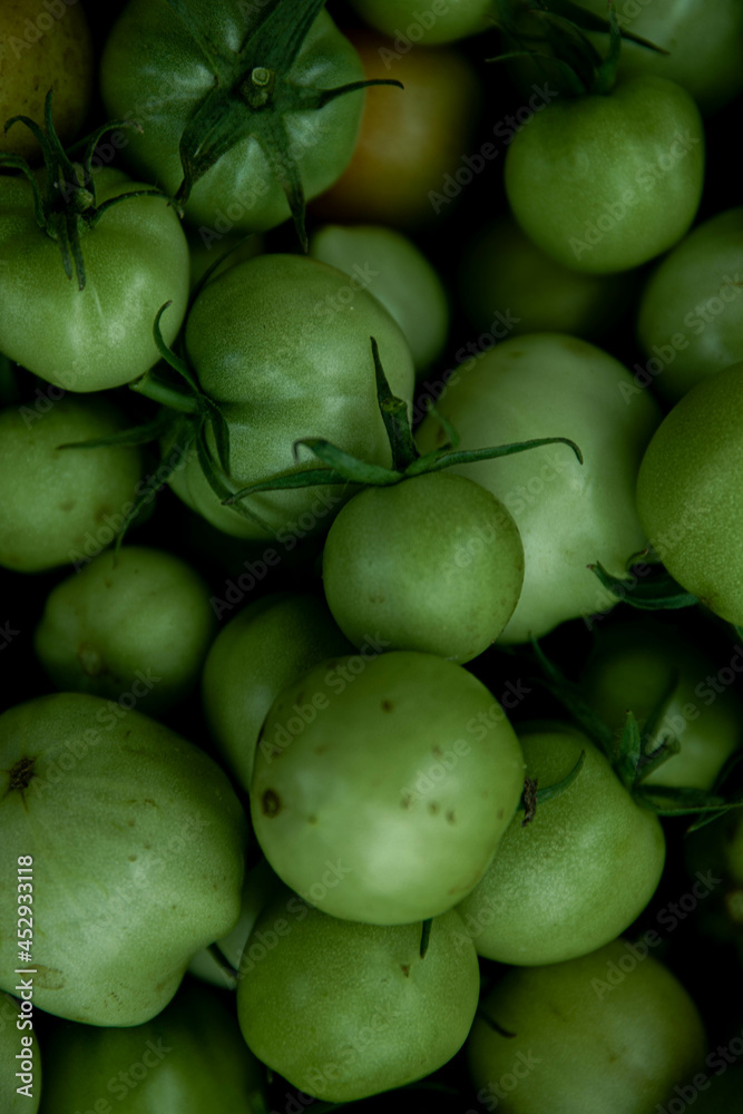 reen tomato (unripe) in wicker basket on wooden background. Unripe green tomato in bowl for fried dish or salted pickled vegetables. Raw green tomato on table for dinner reen tomato (unripe) in wicker basket on wooden background. Unripe green tomato in bowl for fried dish or salted pickled vegetables. Raw green tomato on table for dinner