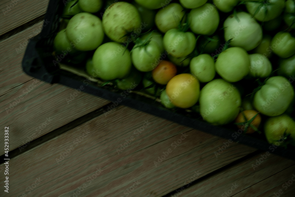 Green tomato (unripe) in wicker basket on wooden background. Unripe green tomato in bowl for fried dish or salted pickled vegetables. Raw green tomato on table for dinner Green tomato (unripe) in wicker basket on wooden background. Unripe green tomato in bowl for fried dish or salted pickled vegetables. Raw green tomato on table for dinner