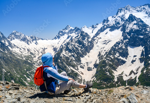 A tourist high in the Dombay Mountains, covered with snow, admires the view photo