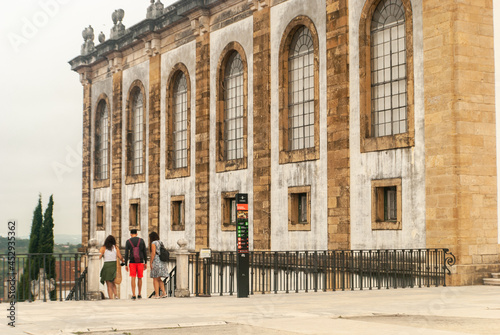 Tourists near the entrance of the Joanina Library at the University of Coimbra Square going down the stairs cloudy day - Portugal photo