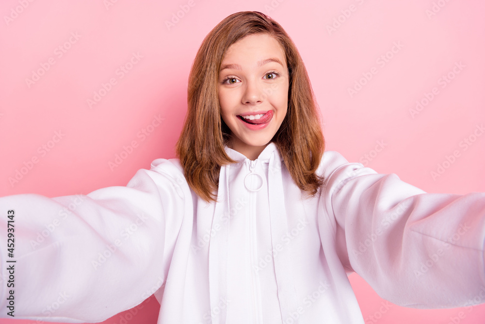 Self-portrait of attractive cheerful girl grimacing having fun licking lip isolated over pink pastel color background Self-portrait of attractive cheerful girl grimacing having fun licking lip isolated over pink pastel color background