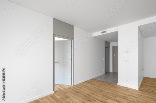 Empty minimalist modern room with white walls  opened grey door  grey floor tiles and oak wood floor