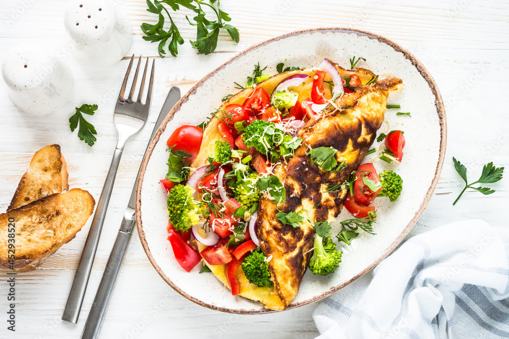 Omelet with fresh vegetables - broccoli, tomatoes and paprika. Healthy breakfast. Top view image. Omelet with fresh vegetables - broccoli, tomatoes and paprika. Healthy breakfast. Top view image.