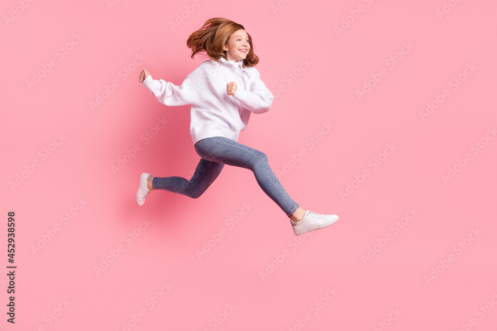 Photo of adorable cute small schoolgirl dressed white sweatshirt jumping running fast looking empty space isolated pink color background