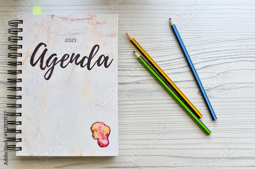 Fotografija Agenda and colored pencils on a wooden table