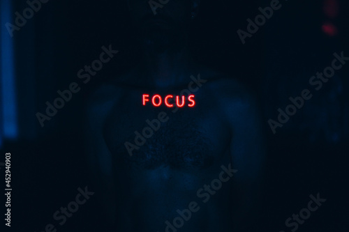 Young man with letters ad Focus word on his face in the dark