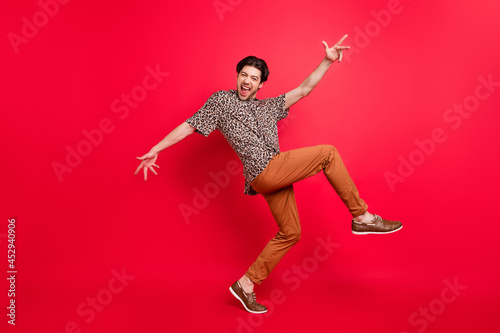 Full size profile side photo of funky careless cheerful smiling man dancing summer vacation isolated on red color background