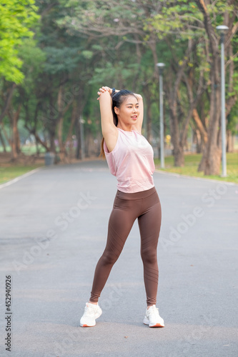 Wide shot and portrait of Asian sport woman do arm and back stretching on road of park during exercise in the morning.