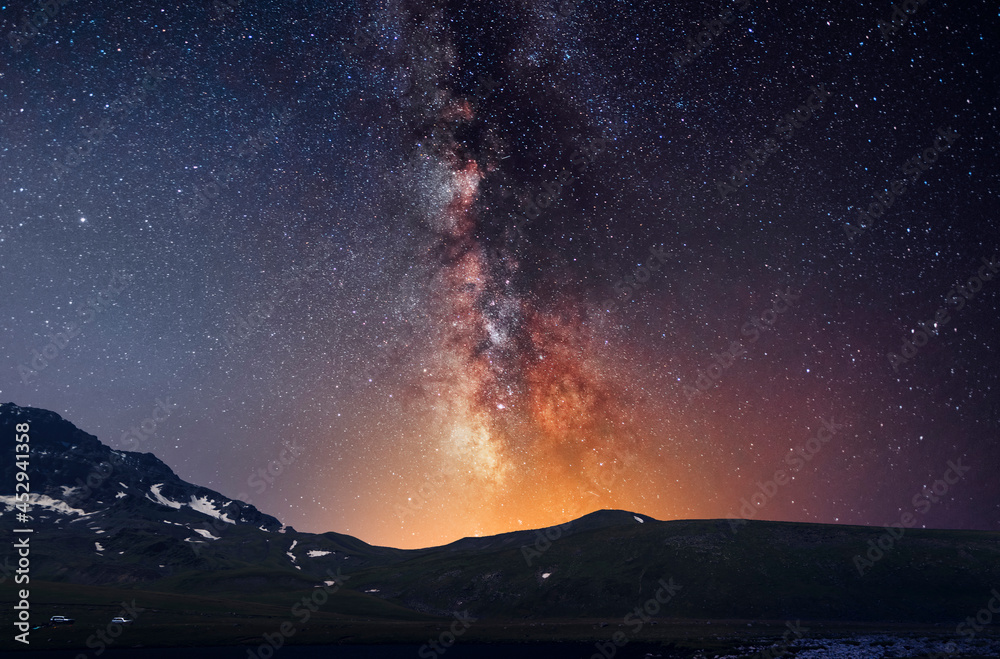 Beautiful night landscape, snow-capped mountains and hill, starry sky with bright milky way galaxy. Night landscape. Astronomical background, night scene.