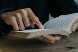 Christian man read bible. Hands folded in prayer on a Holy Bible on wooden table.