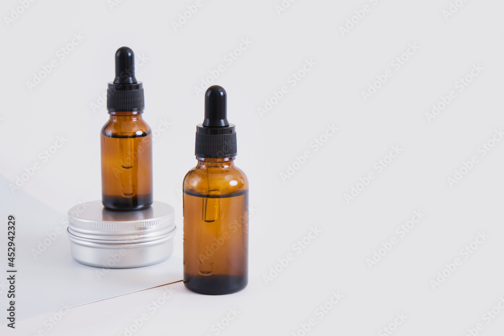 amber brown glass bottles with dropper and aluminum cream jar on gray backround copy space