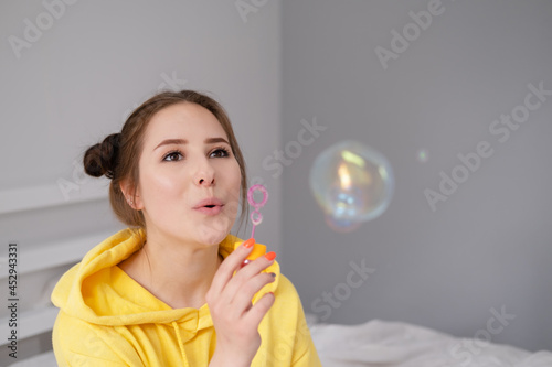 woman in yellow among soap bubbles on grey background