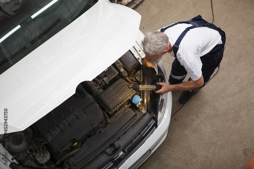 Top view shot of a senior car service worker repairing automobile at the station