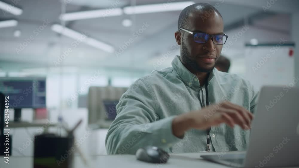 Modern Office: Portrait of Motivated Black IT Programmer Working on Laptop Computer. Male Specialist Create Website, Software Engineer Develop App, Program, Video Game. Stress Free Inclusive Space