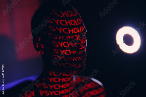 Young adult man with word Psychology on his face in the dark