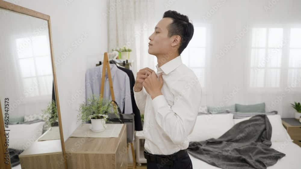 side portrait handsome asian business man doing buttons while looking ...