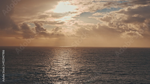 Dramatic sunrise over the ocean. A ray of the sun breaks through the clouds. Sunny path on the water.