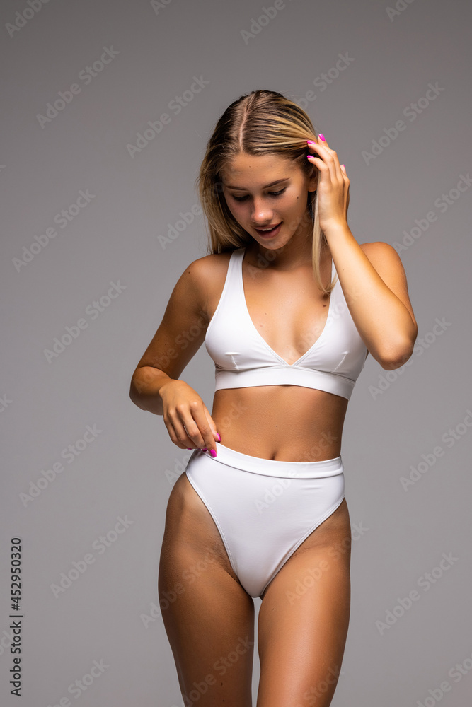 Slim tanned woman's body over gray background. Body care.